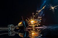 Light bulb with cord illuminated by a sparkler on a black background