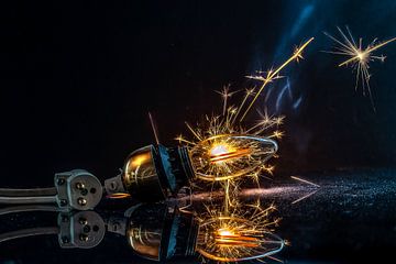 Light bulb with cord illuminated by a sparkler on a black background by Margit Kluthke