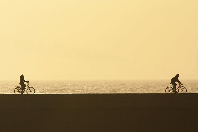 Man en vrouw fietsen bij zonsondergang van Simone Meijer