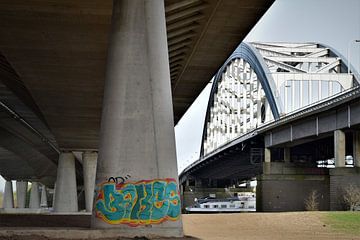 concrete pillar with graffiti under bridge by Maud De Vries