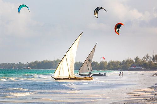 Oude traditionele zeilboten op het strand in Zanzibar met kite surfers op de achtergrond
