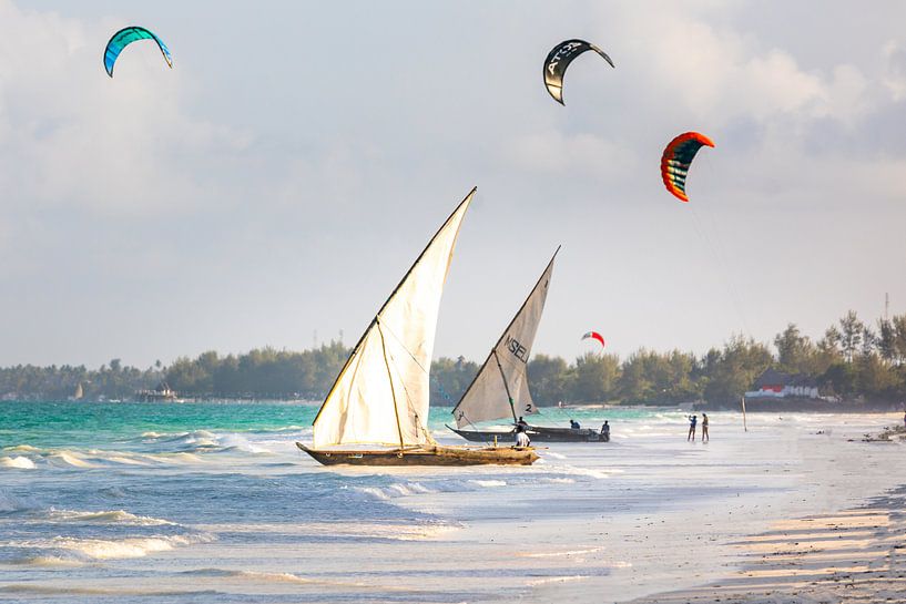 Oude traditionele zeilboten op het strand in Zanzibar met kite surfers op de achtergrond van Michiel Ton
