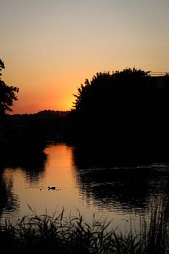 Zonsondergang aan een riviertje van Ken Huysmans