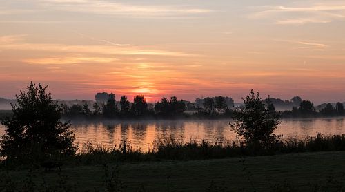 ochtenrood over de maas in limburg tijdens zonsopkomst