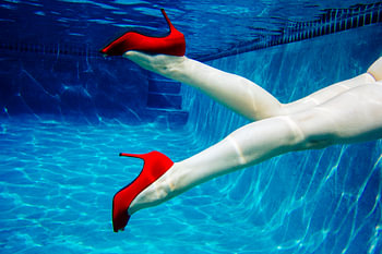 11382168 Women's legs with red high heels underwater in swimming pool