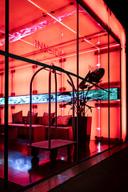 A hotel lobby lit up in neon red with a beautiful glass façade by Your Happy Life