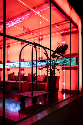 Hotelhal met neonrode verlichting en een prachtige glazen gevel