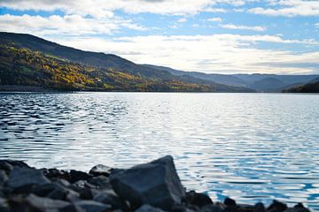 Rustig bergmeer met herfstheuvels en rotsen in het heldere water