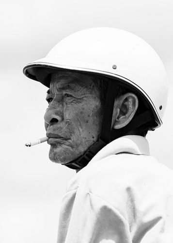 Cambodjaanse man man met helm en sigaret zwart-wit
