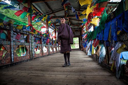 Jonge man in traditionele kleding op loopbrug met gebedsvlaggen in Thimphu Bhutan. Wout Kok One2expo