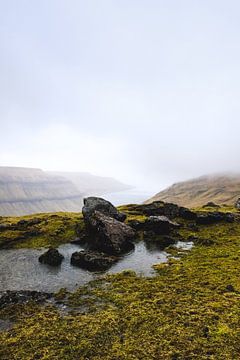 Rotsen op de voorgrond van een typisch Faeröer uitzicht