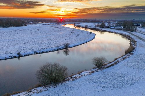 Vecht river flowing through a snowy winter landscape during suns