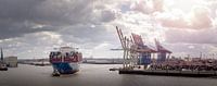 Containerschip in de haven van Hamburg onder bewolkte hemel