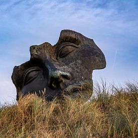 Een beeld van een gezicht in de duinen van scheveningen. Natuur, gras en blauwe achtergrond. van Linda van der Meer