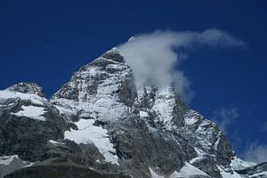De Matterhorn gaat schuil achter een wolkje met stralend blauwe lucht.