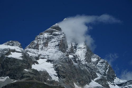 The Matterhorn is hidden behind a small cloud in a bright blue sky. by Gert van Santen