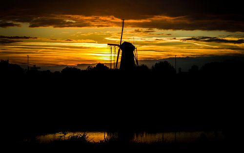 Molen bij zonsondergang en spiegeling in het water