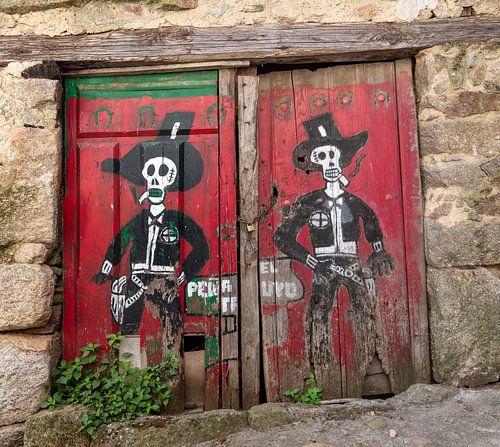 Rode deuren van schuur in Spaanse dorpje Miranda del Castanar met tekening van twee skelet cowboys