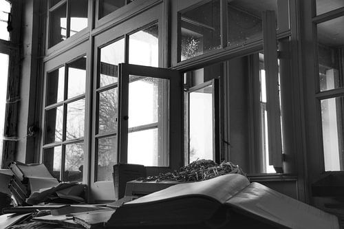 Een verlaten raam in een verlaten kantoor in zwart wit