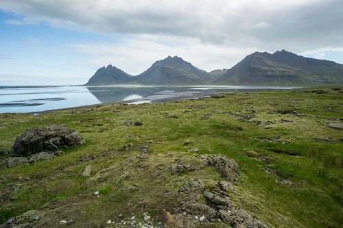 IJsland - Drie bergen die in stil water van meer achter groen grasland natuurlandschap weerspiegelen
