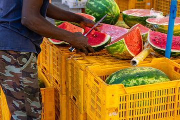Mann schneidet Melone auf dem Wochenmarkt in Italien von Animaflora PicsStock