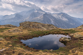 Von Wolken beschattete Gipfel, die sich in einem Pyrenäen-Bergsee spiegeln von PhotoCluster