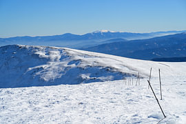 A snow-covered mountain ridge with a view of distant mountain ranges. Lachtal winter sports resort, Styria by Tomherkules