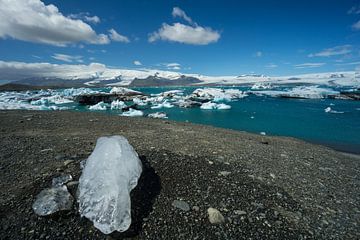 Iceland - Melting peace of ice on hill next to blue glacial lake by adventure-photos