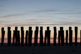 golfbrekers met ondergaande zon op het strand in zeeland