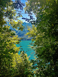 Der Idrosee, umrahmt von sonnenbeschienenem Laub und Bergpanoramen in Italien von Strange Paradise