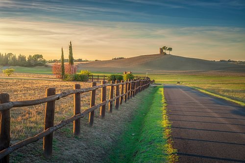 Landweg met houten hek bij zonsondergang in de buurt van Bibbona, Toscane