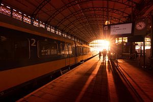 Train station and silhouettes of travelers at sunset von Rob Kints