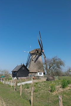 Mooie Hollandse windmolen aan een dijkje met een heldere blauwe lucht