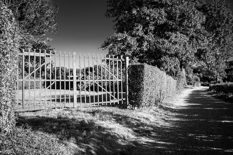 Op slot door poort / hek in het zwart wit schaduw landschap van Limburg van Dorus Marchal