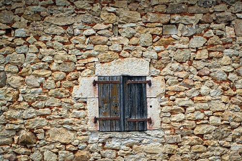 Weathered wooden shutter in a natural stone wall