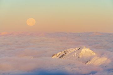 Full moon in winter at sunrise above the clouds