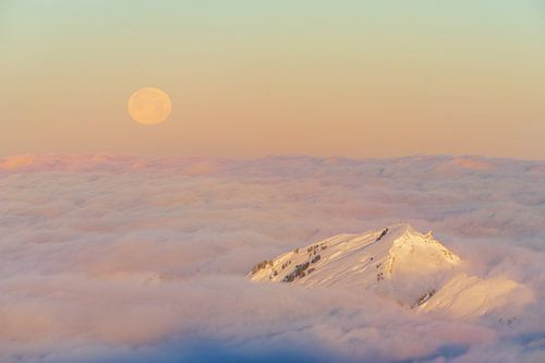 Pleine lune en hiver au lever du soleil au-dessus des nuages