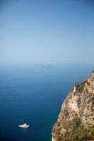 White boat in the sea off the coast of a steep mountain area