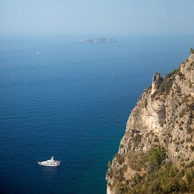 White boat in the sea off the coast of a steep mountain area by Esther esbes - kleurrijke reisfotografie