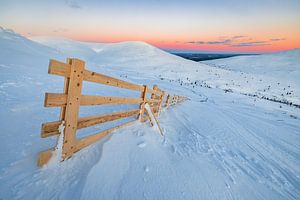 Holzzaun auf dem Gipfel eines verschneiten Berges von Martijn Smeets