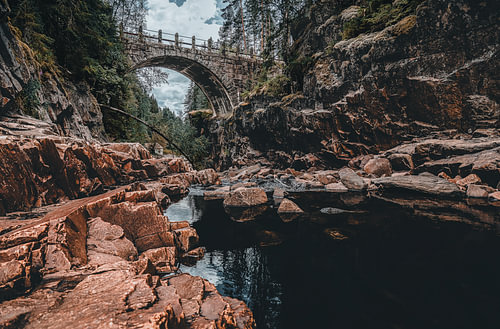 Pont en arc historique en pierre enjambant une rivière dans un paysage scandinave aux allures mélancoliques, dans le Värmland, en Suède