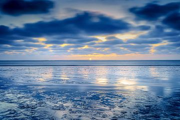 Wadden strand bij zonsondergang met passerende wolken