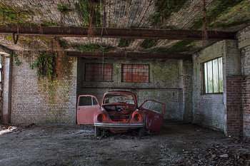 Urbex small red car in a dilapidated garage.