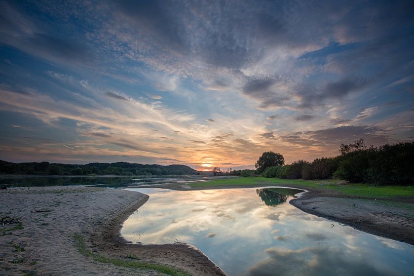 Sonnenuntergang Elbe in Deutschland mit Flare von Wolken und Reflexion des Himmels von Joost Adriaanse