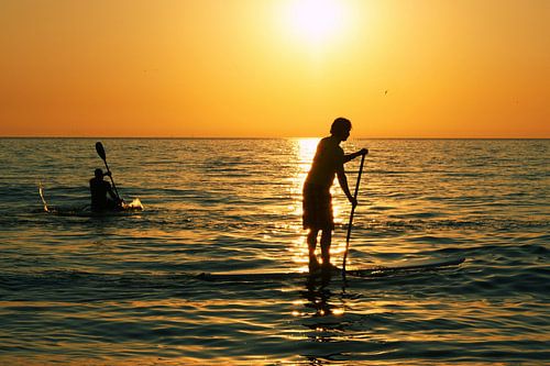 Ondergaande zon - Peddelen in de branding bij Zandvoort