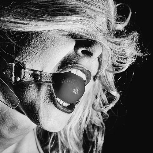 Fetish bdsm stijl foto met een vrouw die een rode mond bal gag in haar mond heeft.