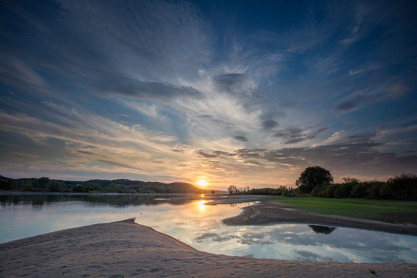 Zonsondergang Elbe rivier in Duitsland met flarde van wolke en reflectie van de lucht en zon van Joost Adriaanse