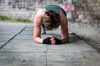 Active 36 year old white woman planking under a bridge outdoors,