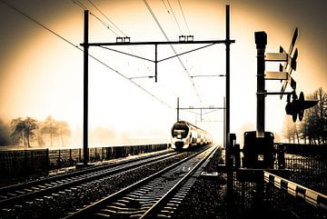 Gekleurde zwart-wit foto van Hollandse trein in mist bij spoorwegovergang van Hans Post
