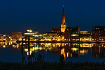 Uitzicht over de Warnow naar de Hanzestad Rostock bij avond van Rico Ködder